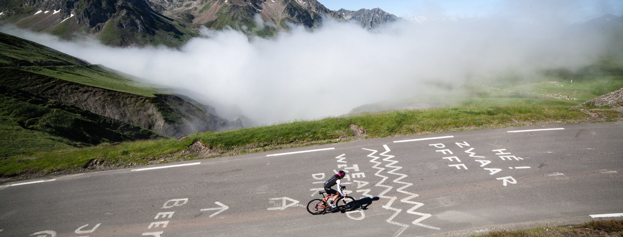 Ciclista en un puerto de montaña sobre el mar de nubes