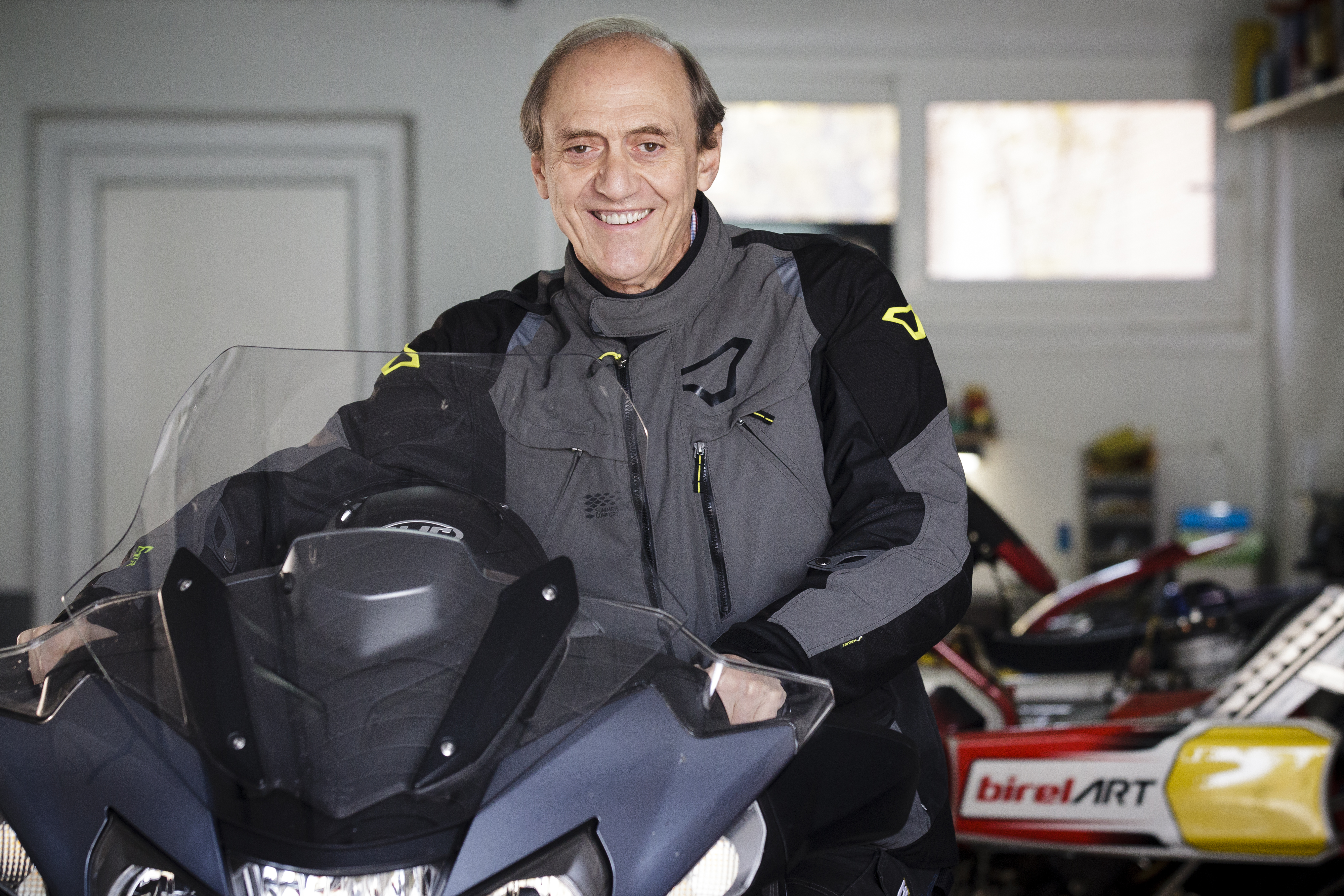 Máximo Sant, con chaqueta de moto, junto a su moto en el taller